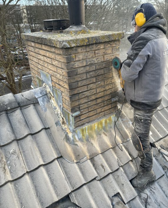 Een werknemer van LS Dakspecialist die voegen uitslijpt op een bakstenen muur.