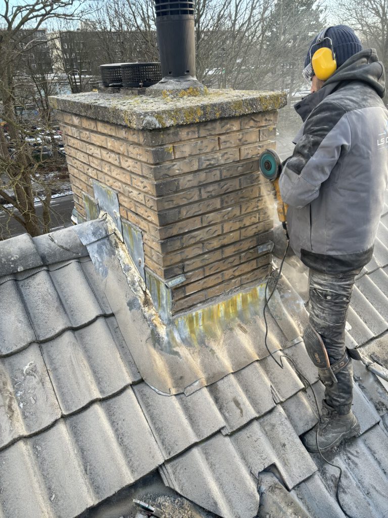 Een werknemer van LS Dakspecialist die voegen uitslijpt op een bakstenen muur.