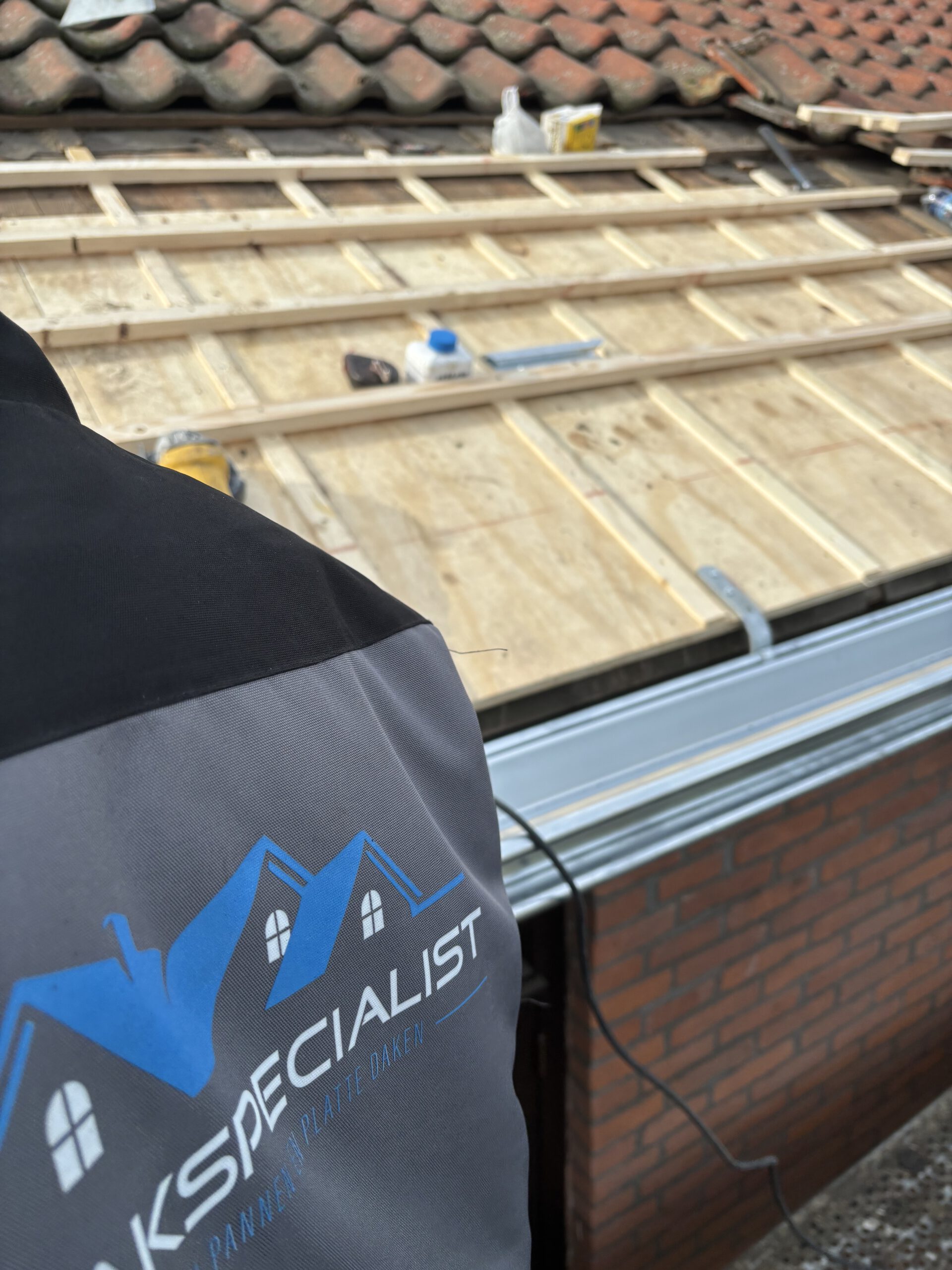 Renovatie van een dakgoot door LS Dakspecialist, waarbij vakmensen bezig zijn met het vervangen van oude onderdelen voor nieuwe, duurzame materialen.