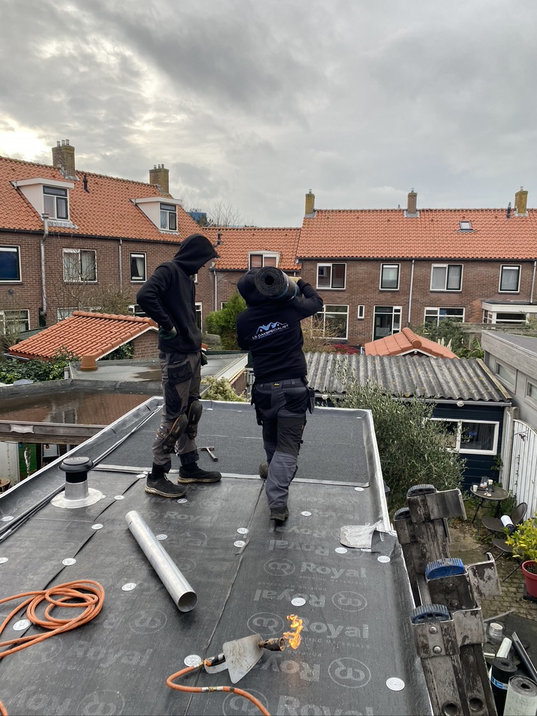 Professionele Dakwerker met Rol Bitumen op Schouder bij LS Dakspecialist